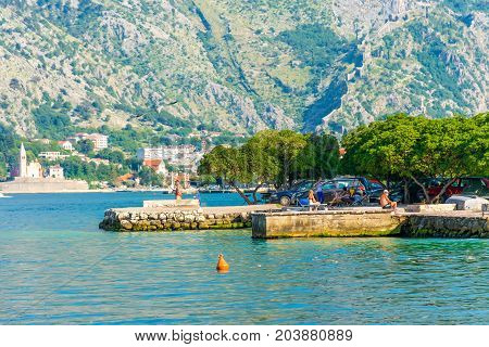 Montenegro, Prcanj - June 04/2017: Tourists Come To The Shore Of The Bay Of Kotor In The Evening To