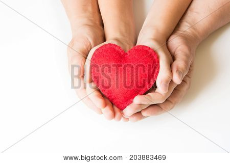 Red felt heart in childs and mens hands on white background. View from above. Copy space.