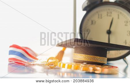 Graduation cap on Golden medals with clock graduate education in university Competitions and Educational study concepts. Success in study famous institution Concept of winner abroad international.