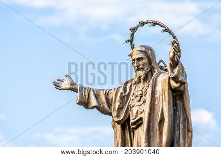 Ile D'Orleans Canada - June 1 2017: Saint-Jean church parish with stone architecture and Jesus Christ statue with outstretched open welcome arms isolated against sky
