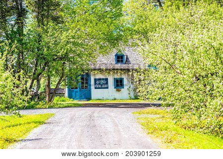 Ile D'Orleans Canada - June 1 2017: Blue house with roadin summer landscape French countryside with Vignoble vineyard or winery sign and dirt road