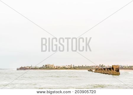 Pillars of the old railroad bridge over the mouth Swakop River with part of Swakopmund in the back