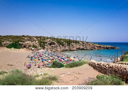 View of the beach of Calamosche Vendicari in Sicily - Tourists families sunbeds and umbrellas on summer hot day