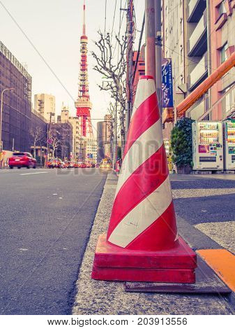 HAKONE, JAPAN - JULY 02, 2017: Close up of a orange cone in the streets with a huge red tower behind, at Hakone town.
