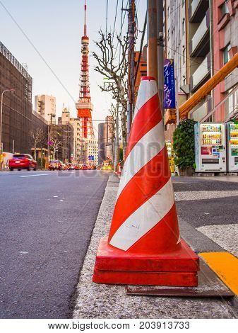 HAKONE, JAPAN - JULY 02, 2017: Close up of a orange cone in the streets with a huge red tower behind, at Hakone town.