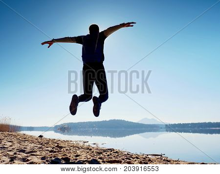 Jumping Man. Sportsman Crazy Jumping  And Jogging On Beach During The Sunrise