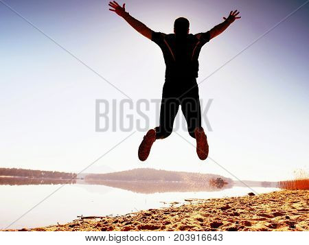 Jumping Man. Sportsman Crazy Jumping  And Jogging On Beach During The Sunrise