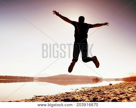 Jumping Man. Sportsman Crazy Jumping  And Jogging On Beach During The Sunrise