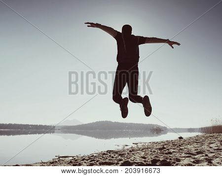 Jumping Man. Sportsman Crazy Jumping  And Jogging On Beach During The Sunrise