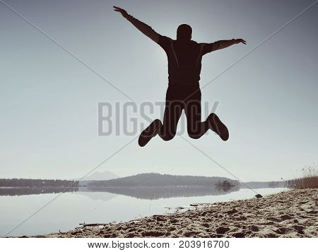 Jumping Man. Sportsman Crazy Jumping  And Jogging On Beach During The Sunrise