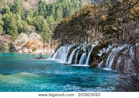 Waterfalls in JiuZhaiGou. Jiuzhaigou , Sichuan, China. Picturesque nature in JiuZhaiGou. Flow of water over the rocks into the lake against the backdrop of mountains and sky