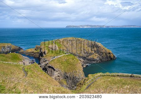 Ballintoy, United Kingdom - May 2, 2016: Carrick-a-Rede Rope Bridge, a popular tourist destination in Northern Ireland. Tourists passing the bridge.