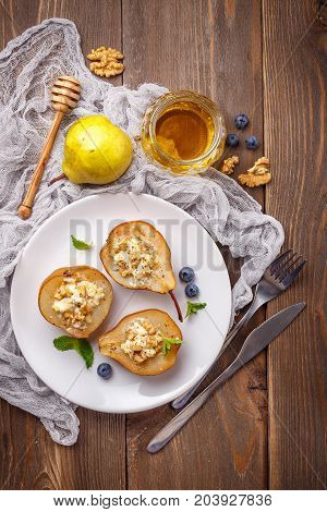 Pears baked with Ricotta cheese nuts honey and cinnamon on rustic wooden background. Top view