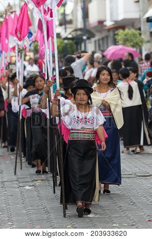 April 14 2017 CotacachiEcuador: indigenous kechwa women in traditional dress walking with religious flags at the Easter procession