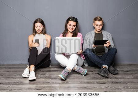 Beautiful Young People Of Different Nationalities Are Using Gadgets And Smiling, Standing Against Wh