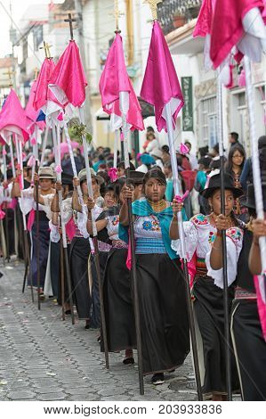 April 14 2017 CotacachiEcuador: indigenous kechwa women in traditional dress walking with religious flags at the Easter procession