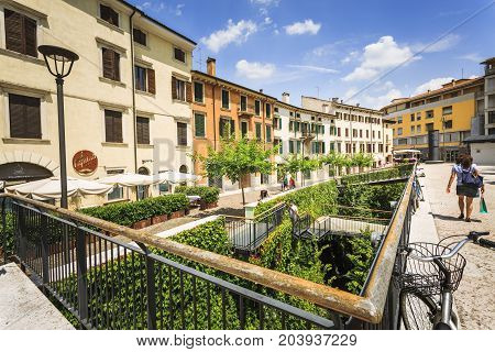 VERONA ITALY - JUNE 25 2016: Picture from Piazza Cittadella with restaurants trees people and a wide green garden with stairs in a sunny day with clouds. Verona Italy.