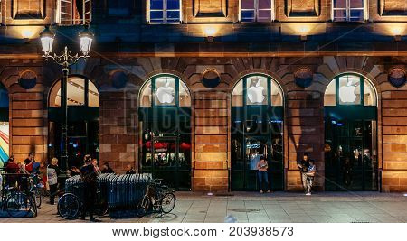 STRASBOURG FRANCE - SEPT 18 2014: Night view of Apple Store facade builing with impatient customers waiting in queue and tents for the upcoming Apple iPhone Apple Watch and other new products