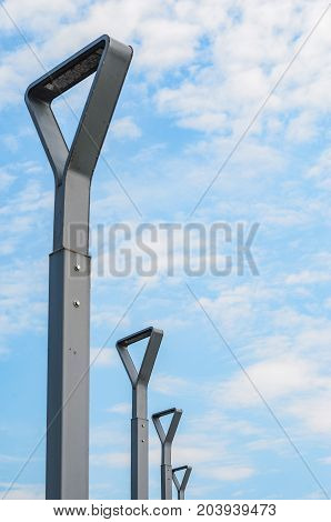Four Street Lamps with Blue Sky Background. Modern Street Lights Minimalist Shapes in a Row Perspective View