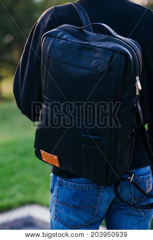 The guy with a black leather backpack. City landscape.