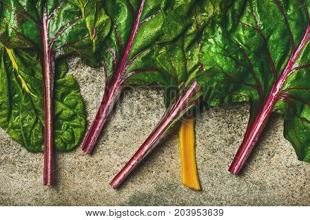 Flat-lay of fresh leaves of swiss chard over concrete stone background, top view, horizontal composition. Clean eating, vegetarian, vegan, alcaline diet, organic, healthy cooking concept