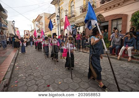 April 14 2017 Cotacachi Ecuador: indigenous kechwa girls in traditional dress walking with religious flags at the Easter procession