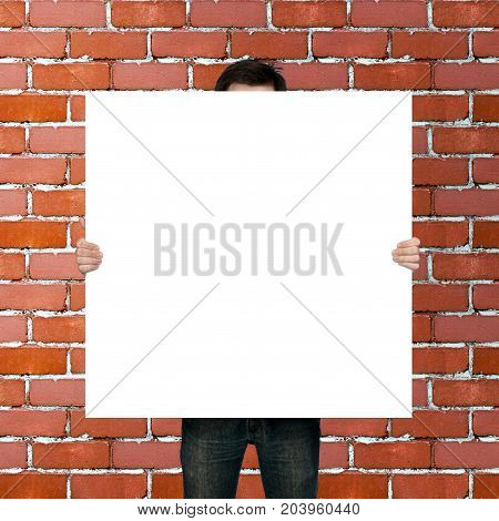 man holding blank poster on red brick background
