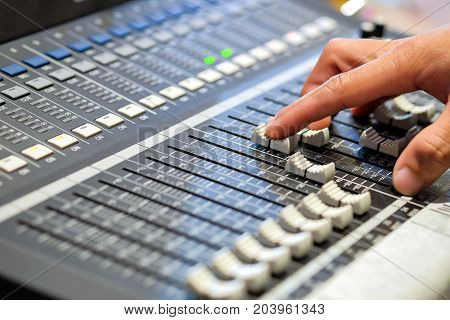 Sound engineer's fingers are pressing the button audio controller in recording room.