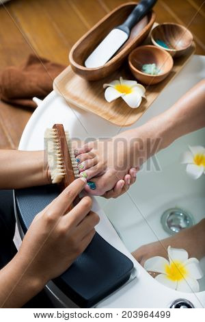 Manicure and pedicure series: Pedicurist brushing customer's foot in pedicure bowls