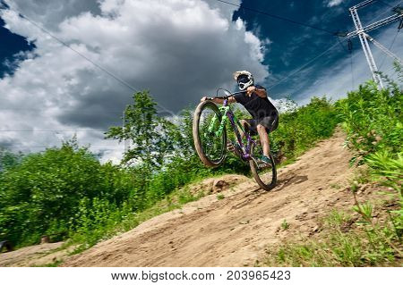 Moscow Russia - July 6 2017: Mountain bike cyclist doing wheelie stunt on a mtb bike. Biker riding extreme sport bicycle. Cool athlete cyclist on a bike. MTB biking.