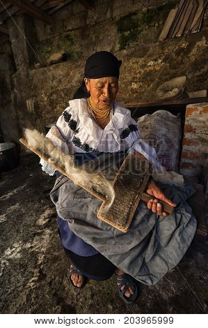 April 21 2017 Iluman Ecuador: elderly quechua woman combing natural wool for hat manufacturing in her home
