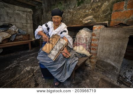April 21 2017 Iluman Ecuador: elderly quechua woman combing natural wool for hat manufacturing in her home