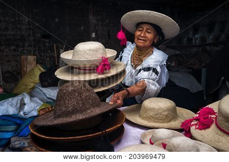 April 21 2017 Iluman Ecuador: quechua woman presenting a variety of traditional felt hats her shops produces