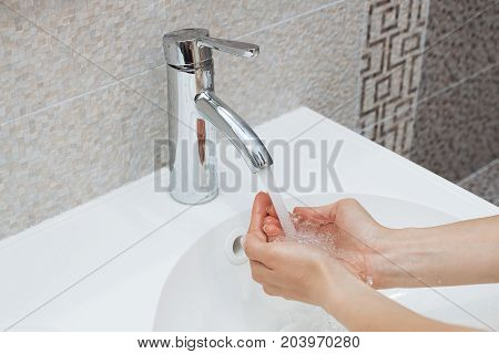 Washing of hands with soap under running water.