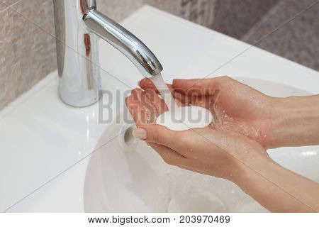Washing of hands with soap under running water.