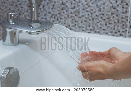 Washing of hands with soap under running water.