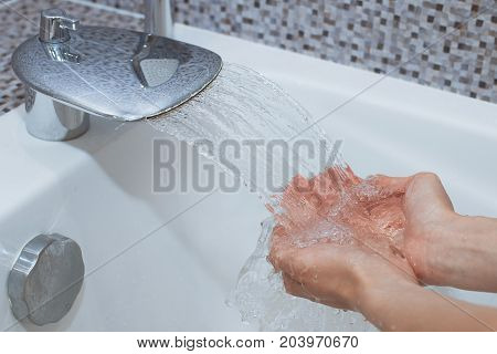 Washing of hands with soap under running water.