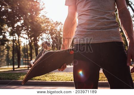 Unrecognizable young man with skateboard in hands. Extreme sport challenge and competition, readiness for adventure and confidence. Skateboarding urban lifestyle and culture