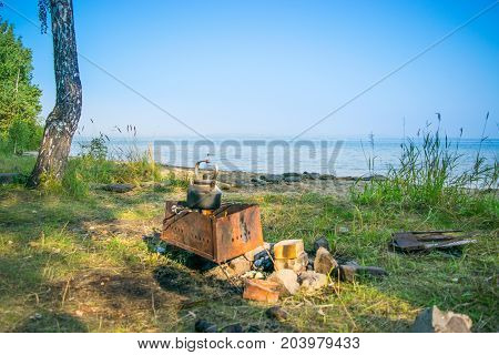 Bloated teakettle on a fire at a bank of a lake - hiking landscape,  Uveldy, The Urals, Russia