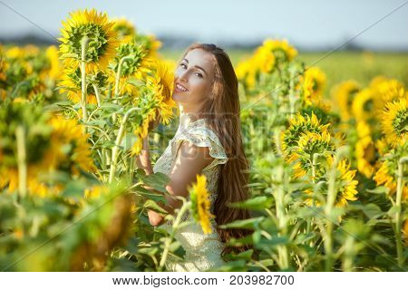 Joyful woman in a field among blooming sunflowers.