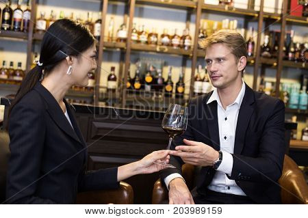 Woman Send Wine To Man With Attracitve Smiling At Restaurant. People Drinking Wine With Relax Emotio