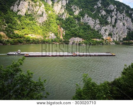 Danube Canyon Between Serbia And Romania. Barge Floating On The Danube. Transportation On The Water.