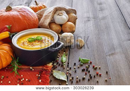 Spicy Pumpkin Creme Soup With Garlic, Onion. Chili And Ginger. The Soups Is Served In Ceramic Pan Wi