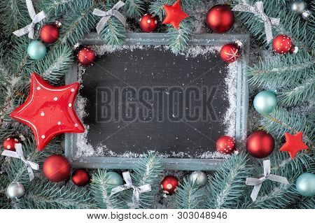 Green And Red Christmas Background With Decorated Chalk Board. Decorated Fir Twigs Around Chalk Boar