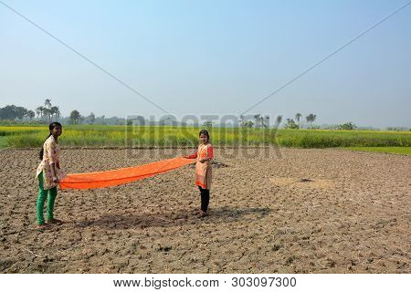 Two Indian Girls Wearing Traditional Colorful Salwar Kameez Flying Their Urna/cloth In The Field Wit