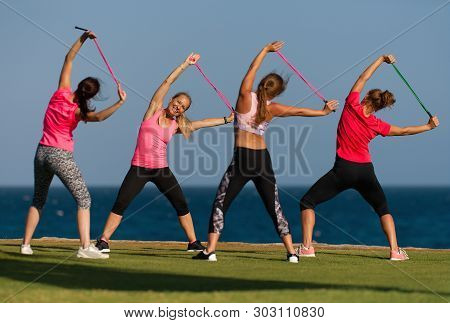 Group Of Young People Doing Their Fitness Training By The Sea, Using Skipping Rope