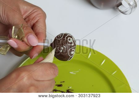 A Woman Decorates With The Help Of White Chocolate Popcake Glazed With Dark Chocolate.