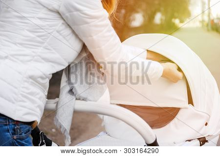 Woman Strolling With White Baby-carriage. Female Hands Close Modular Pop-up White Baby-carriage To R