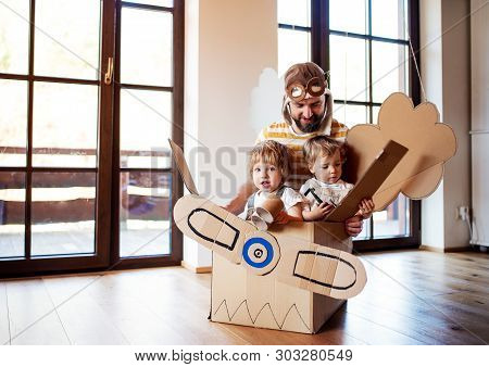 A Father And Toddler Chidlren Playing With Carton Plane Indoors At Home.