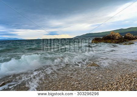 Waves Coming And Going On A Pebbely Beach